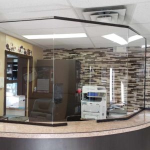 A glass sneeze guard installed in the service desk of an office.